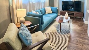 Sala de estar com sofá, mesa de centro, televisão e ventilador de teto.
