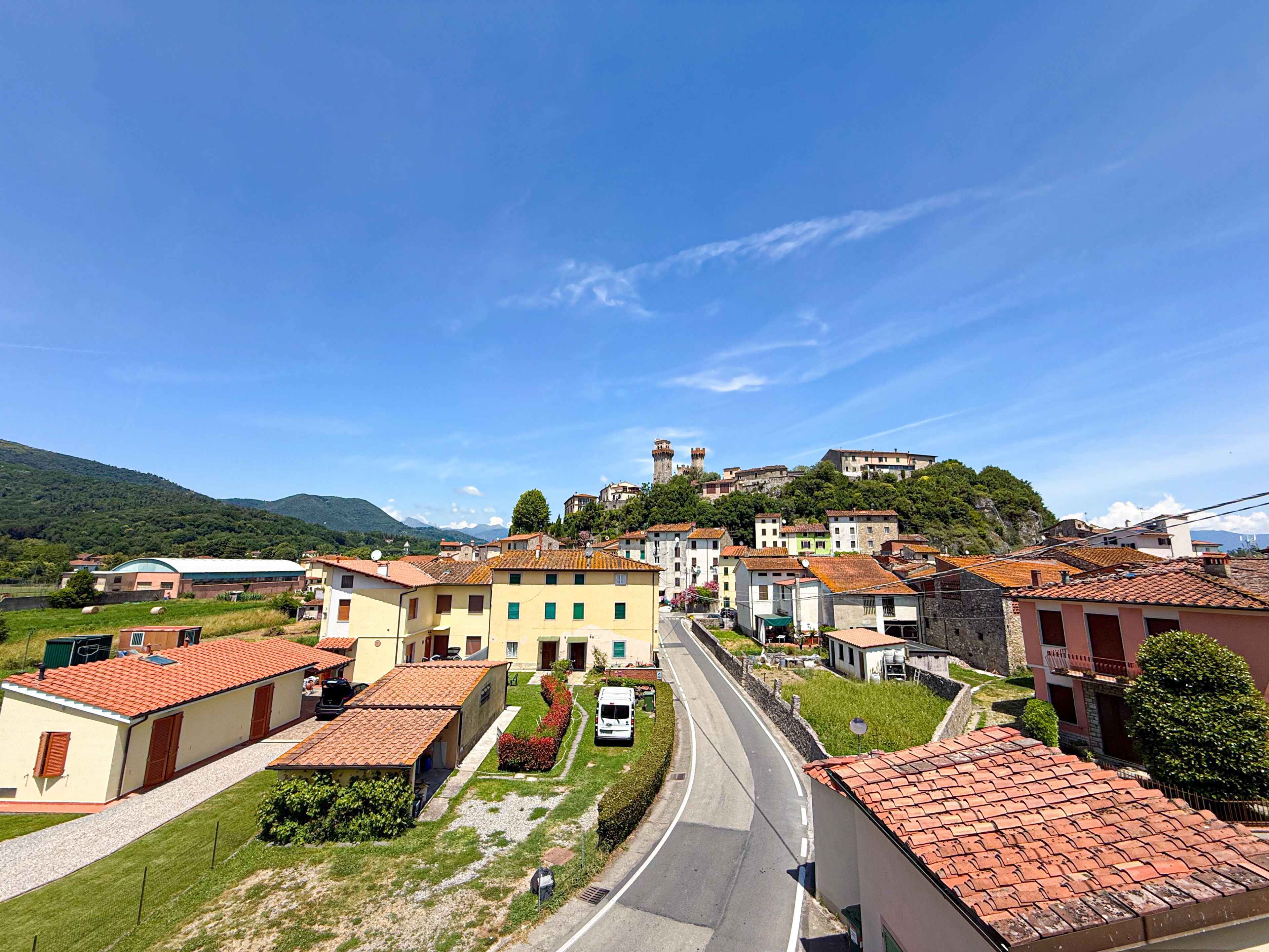 A town with buildings, a road, and a hill with a tower.