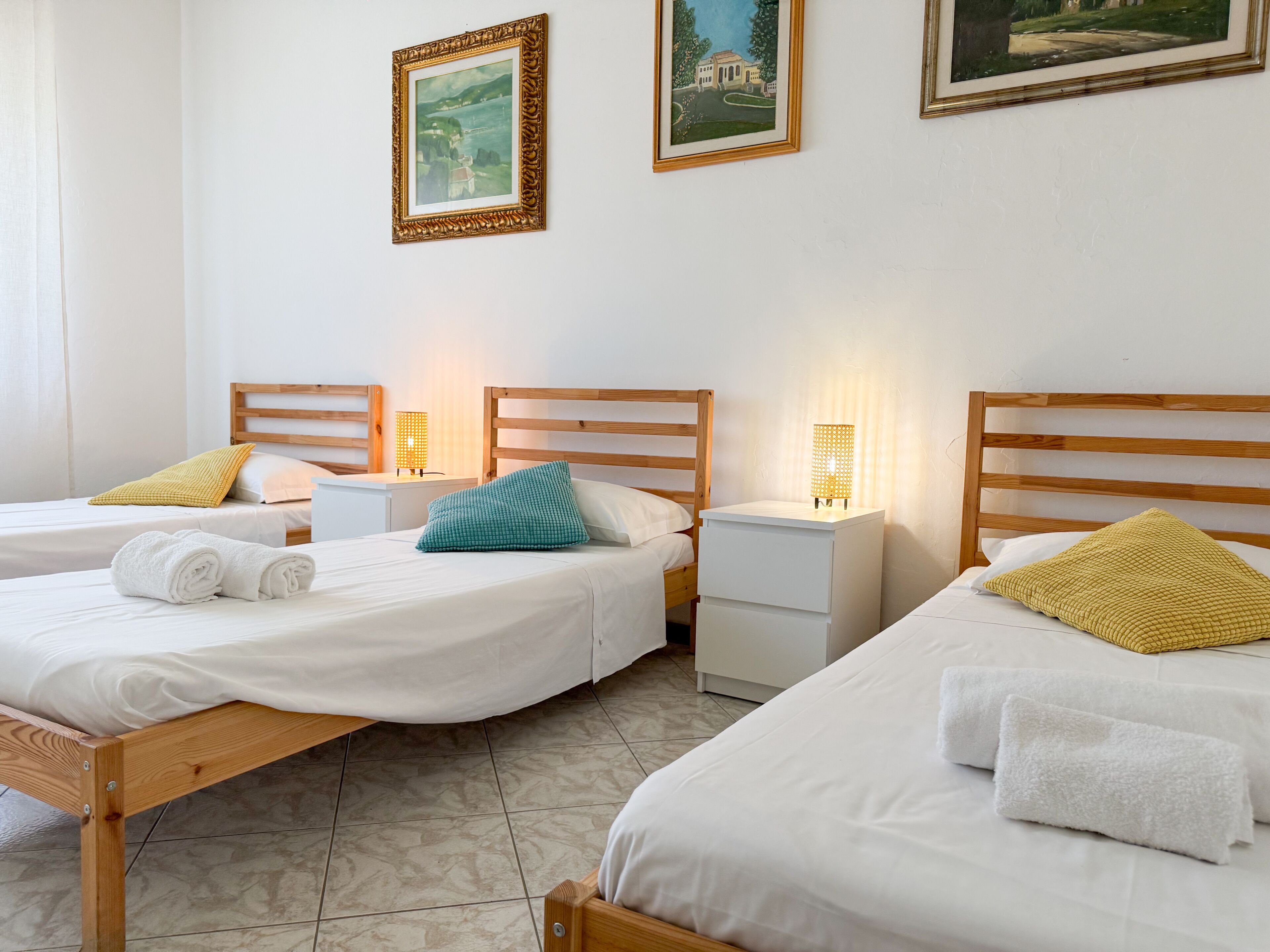 A hotel room with two wooden beds, white bedding, and bedside lamps.