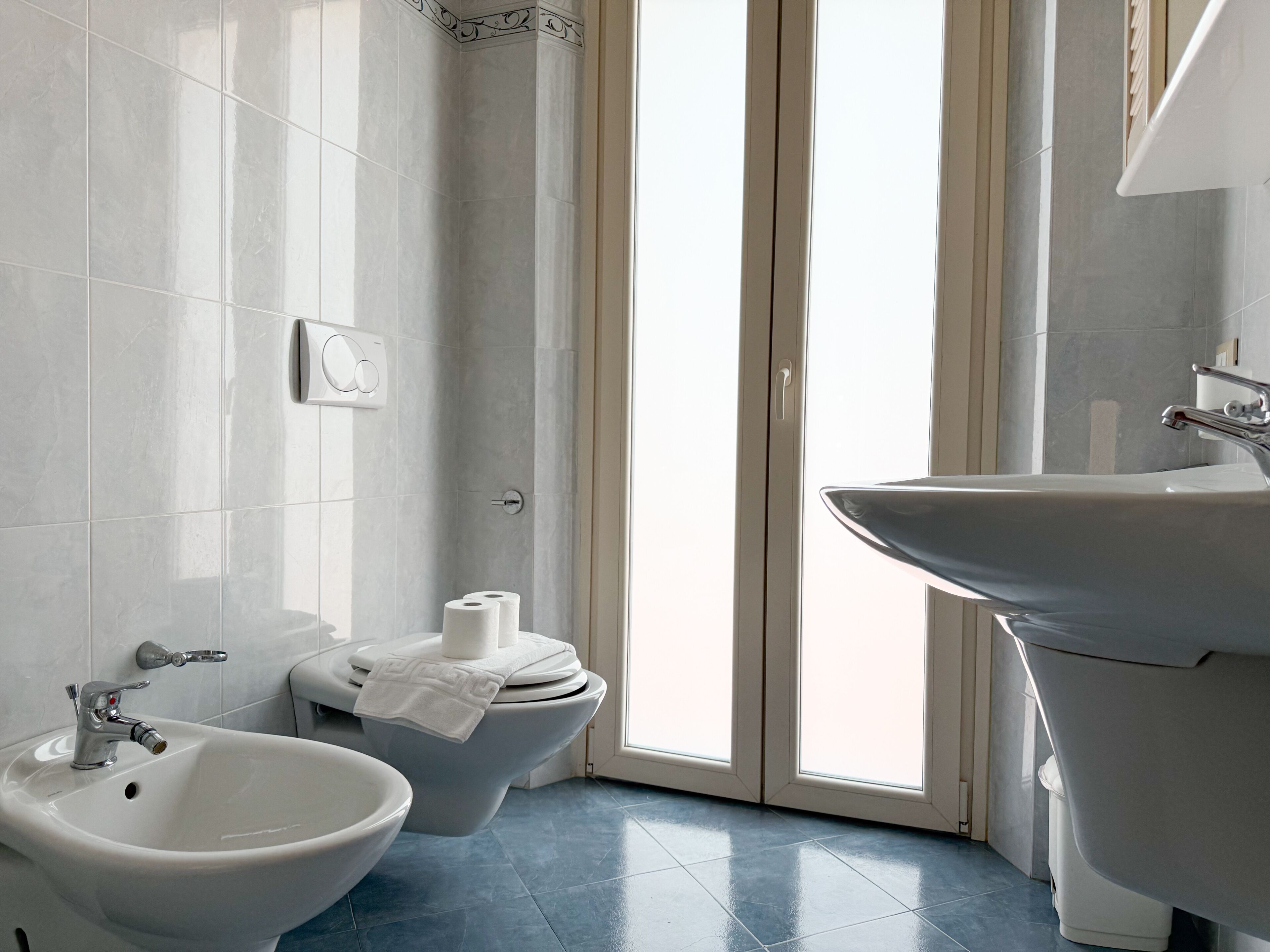 A bathroom with a bidet, toilet, and sink.