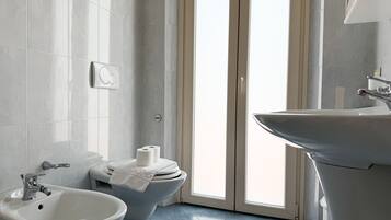 A bathroom with a bidet, toilet, and sink.