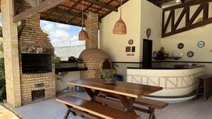 An outdoor kitchen area with a brick oven, wooden table, and benches.
