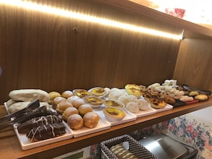 Baked goods are arranged on a counter, offering a variety of pastries, tarts, muffins, and cookies.