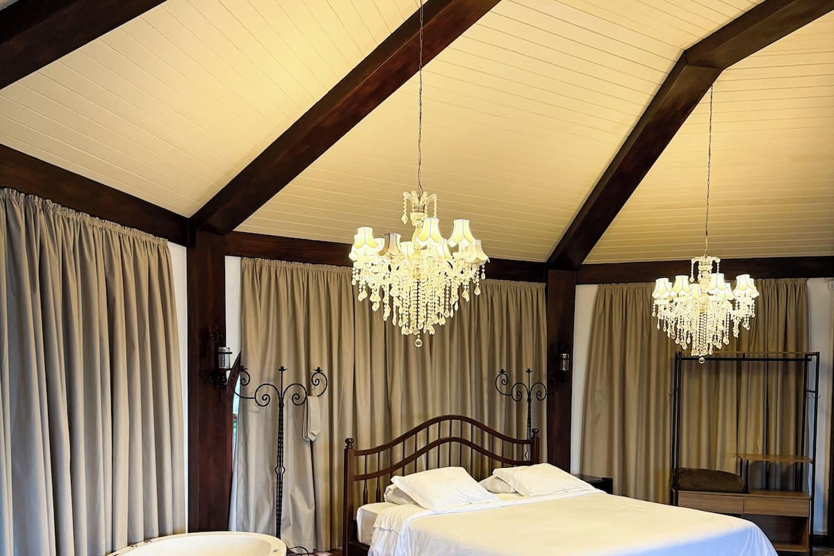 Een slaapkamer met een groot bed, een badkuip en twee kroonluchters.