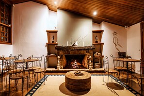 A cozy room with a fireplace, wooden furniture, and a patterned floor. -  Smart Hotel Reserva Campos do Jordão (Campos do Jordão)