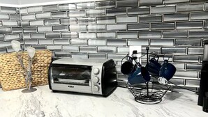 Eine Küche mit modernem Design, inklusive Marmorarbeitsplatte, Toaster und einer Körbe mit Küchenutensilien.