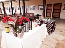Una mesa dispuesta con diversos objetos, entre ellos una cafetera, un termo y recipientes, probablemente para un servicio de desayuno o brunch.
