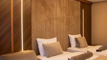 Une chambre d’hôtel moderne avec deux lits, un canapé et un mur décoratif en bois.