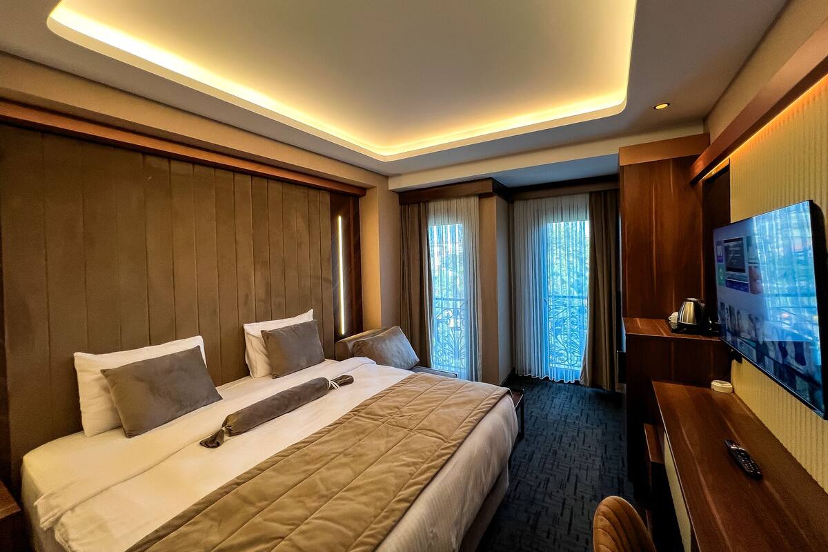 A hotel room with a large bed, a desk, and a television.