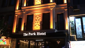 Le Park Hotel se distingue par son entrée imposante, son balcon et son panneau indicateur.