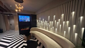 Un salon moderne avec un canapé aux lignes courbes, une cheminée, un téléviseur à écran plat et un sol à motifs.