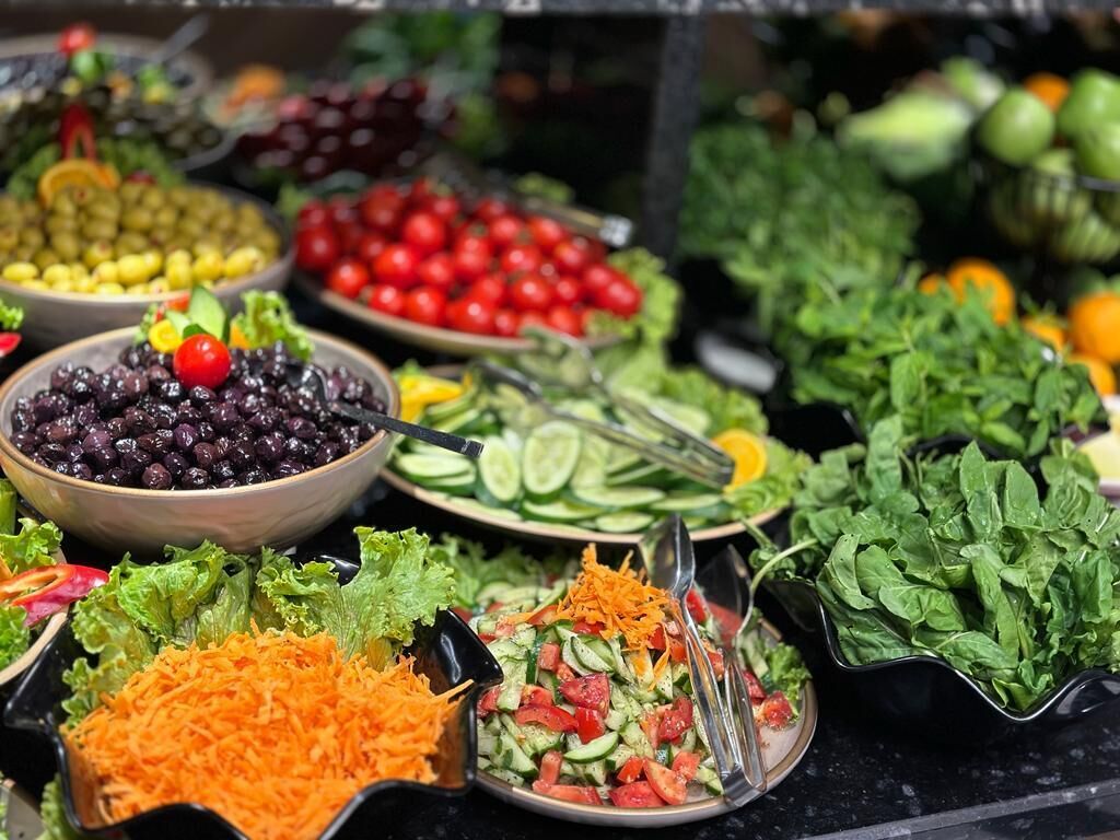 A variety of fresh vegetables and salads displayed in bowls and plates.