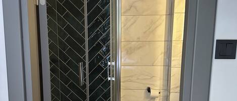 A bathroom with a glass-enclosed shower, a toilet, and a sink.