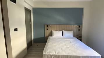 A bedroom with a bed, a wooden headboard, a ceiling light fixture, and a door.