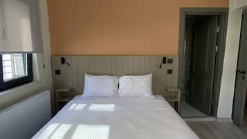 A large bed with white linens, a wooden headboard, and two bedside tables with lamps.