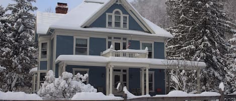 Uma casa de dois andares com telhado coberto de neve e varanda.