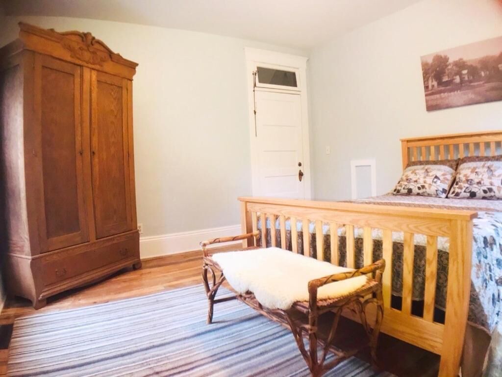 Un dormitorio con un armario de madera, una cama con colcha estampada y una alfombra a rayas.