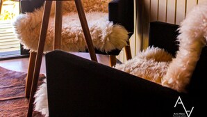 Makuuhuone ullakkokerroksessa, jossa on puinen pöytä, pehmeät tuolit ja näkymä ulos.