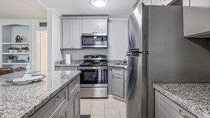 A modern kitchen with granite countertops, stainless steel appliances, and white cabinetry. - The Secret Bayou Retreat to Rest and Unwind - HAR1 (Iowa)