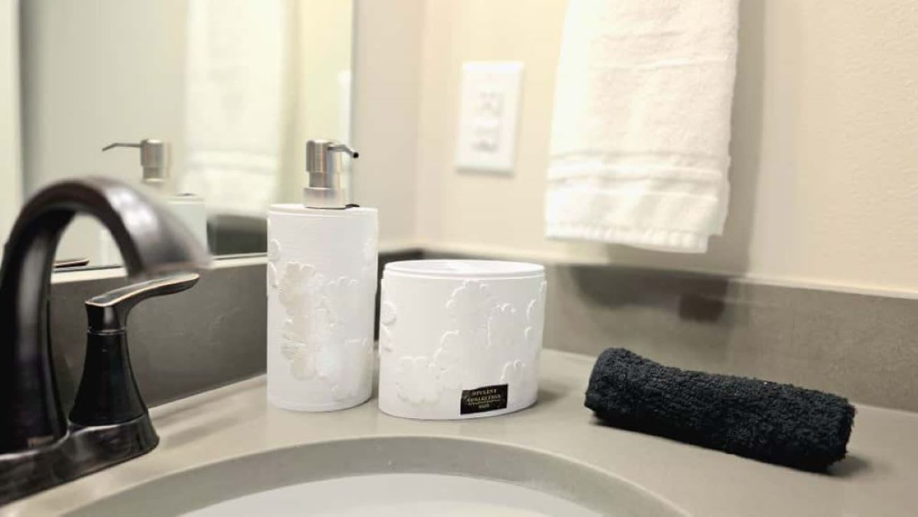 A bathroom sink with a faucet, a soap dispenser, and a towel.