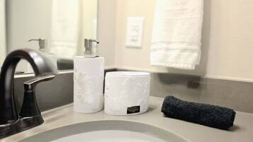 A bathroom sink with a faucet, a soap dispenser, and a towel.