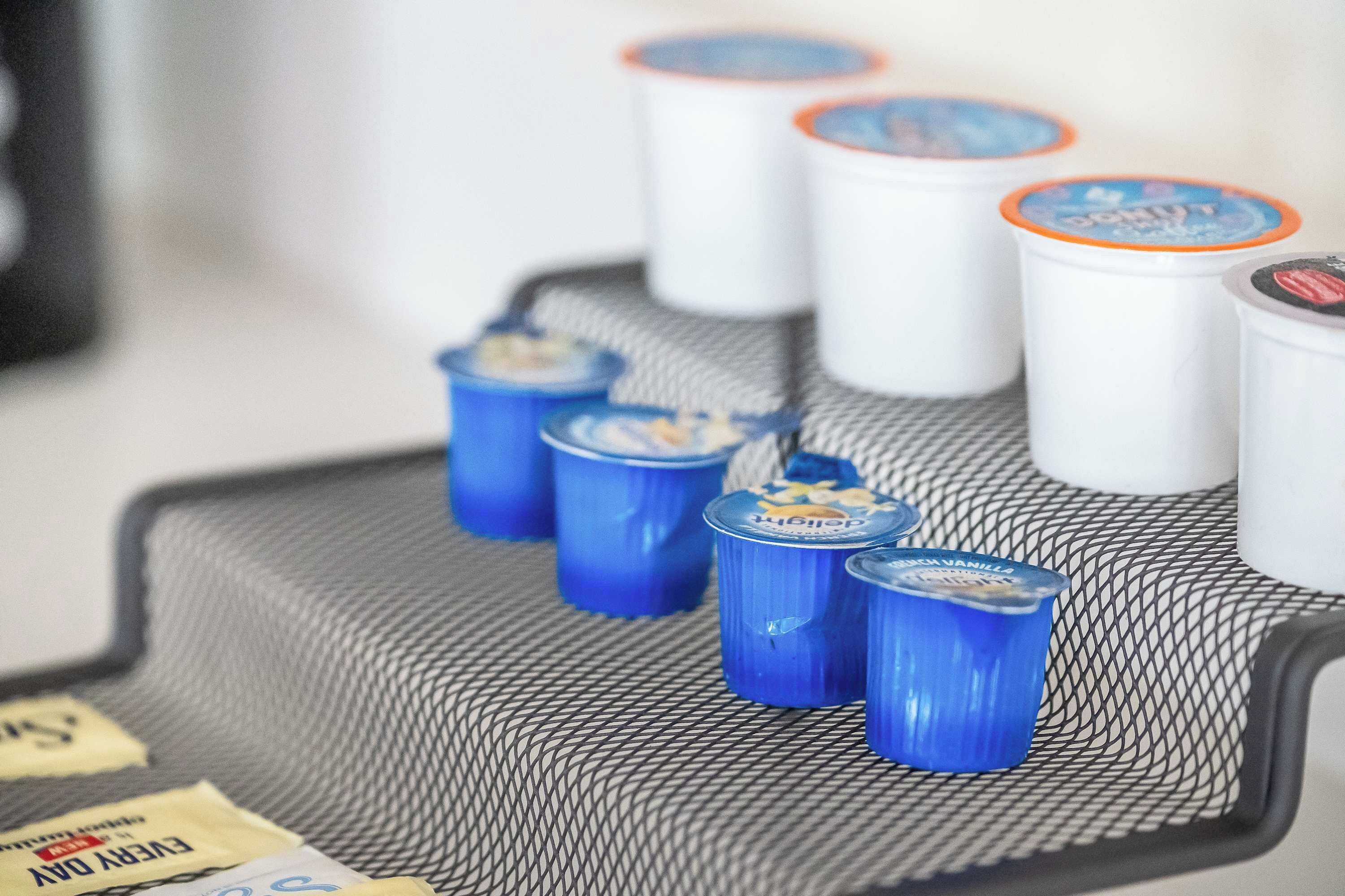 A tray with several beverage containers, some with blue lids and others with white lids, on a textured surface.