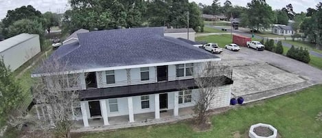 A two-story building with a flat roof, a covered parking area, and a small garden.
