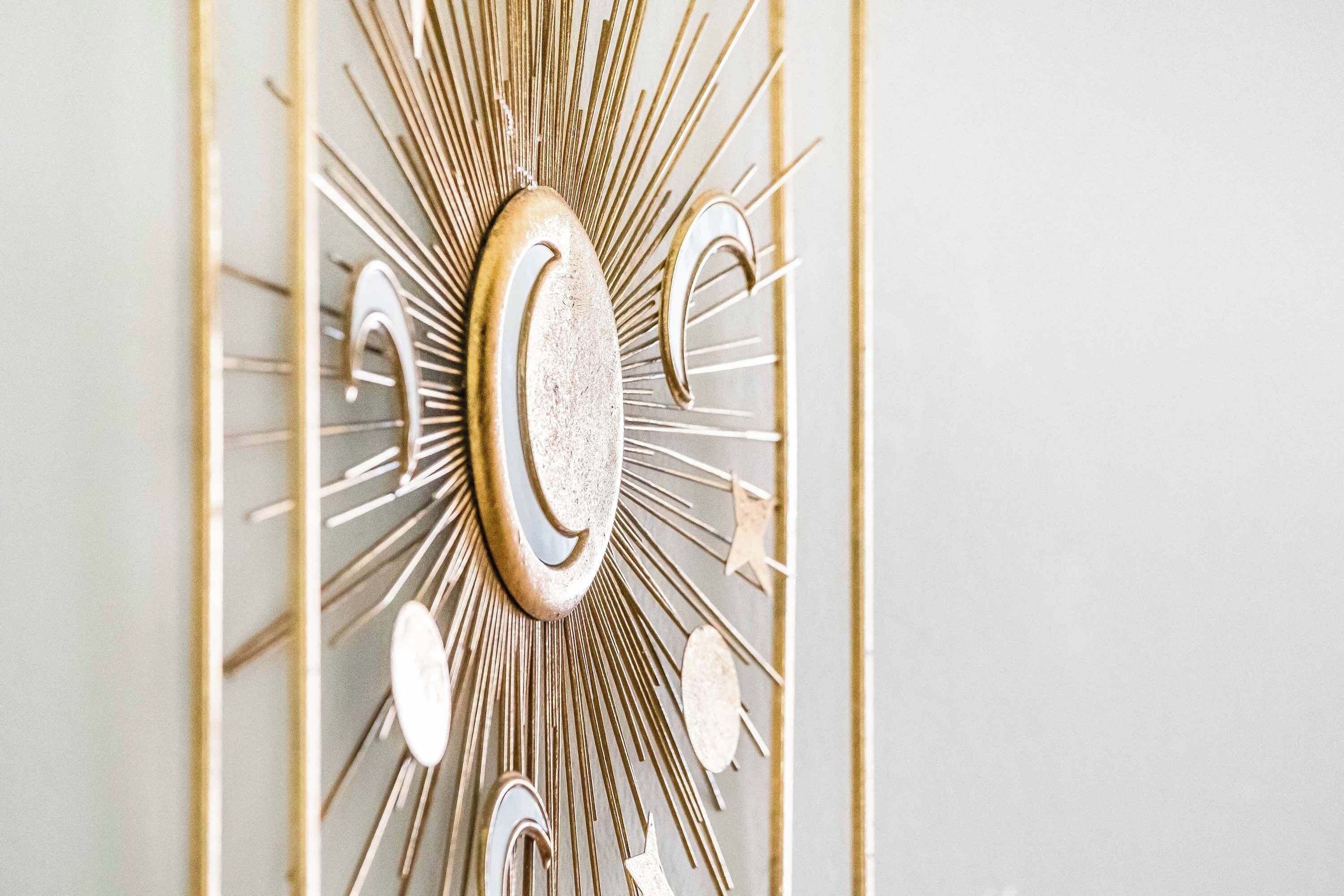 Un elemento decorativo a parete con motivo a raggiera e un elemento circolare centrale.