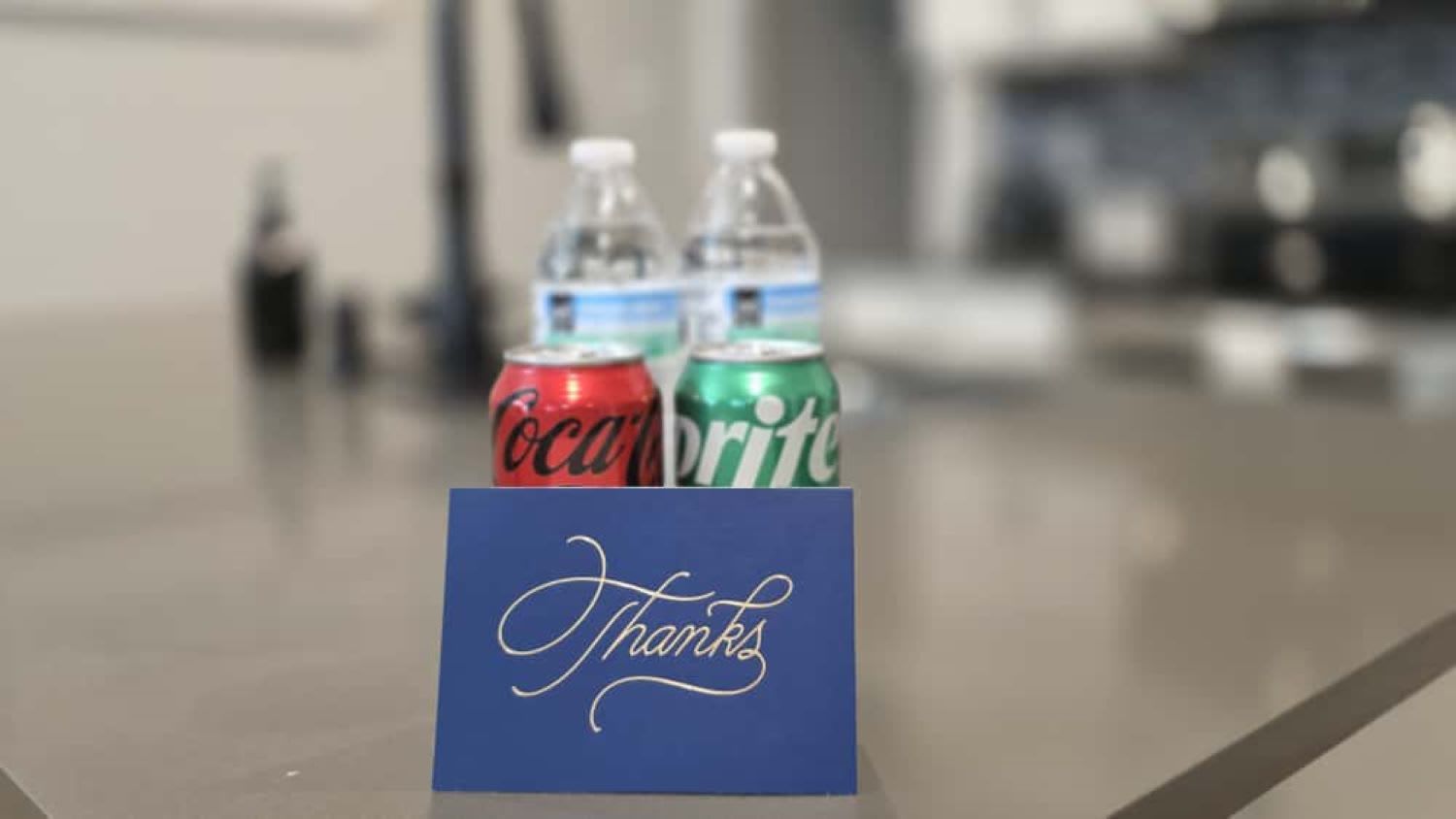 A thank you card with two beverage cans, one red and one green, on a counter.