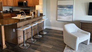 A modern kitchen with wooden cabinets, a stainless steel sink, and a bar area with stools. - 3 bedroom townhouse in a Golf community near Disney parks. (Kissimmee)