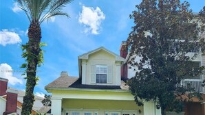 A two-story house with a front porch, a small balcony, and a garage. - 3 bedroom townhouse in a Golf community near Disney parks. (Kissimmee)