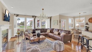 A spacious living room with a large sectional sofa, a fireplace, a chandelier, and a view of the outside. -  truly stunning lakefront with immediate access to all the city has to offer. (Cypress)