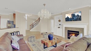 A spacious living room with a fireplace, a chandelier, and a large TV mounted on the wall. -  truly stunning lakefront with immediate access to all the city has to offer. (Cypress)