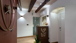 Un espace d’accueil doté d’un plancher en bois, d’un comptoir de réception portant l’inscription « Chambres du SOFI Center » et d’une porte en verre donnant sur une autre pièce.