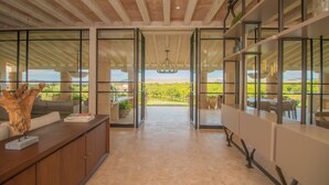Une pièce spacieuse dotée d’une grande fenêtre, d’un plafond en bois et offrant une vue sur l’extérieur.