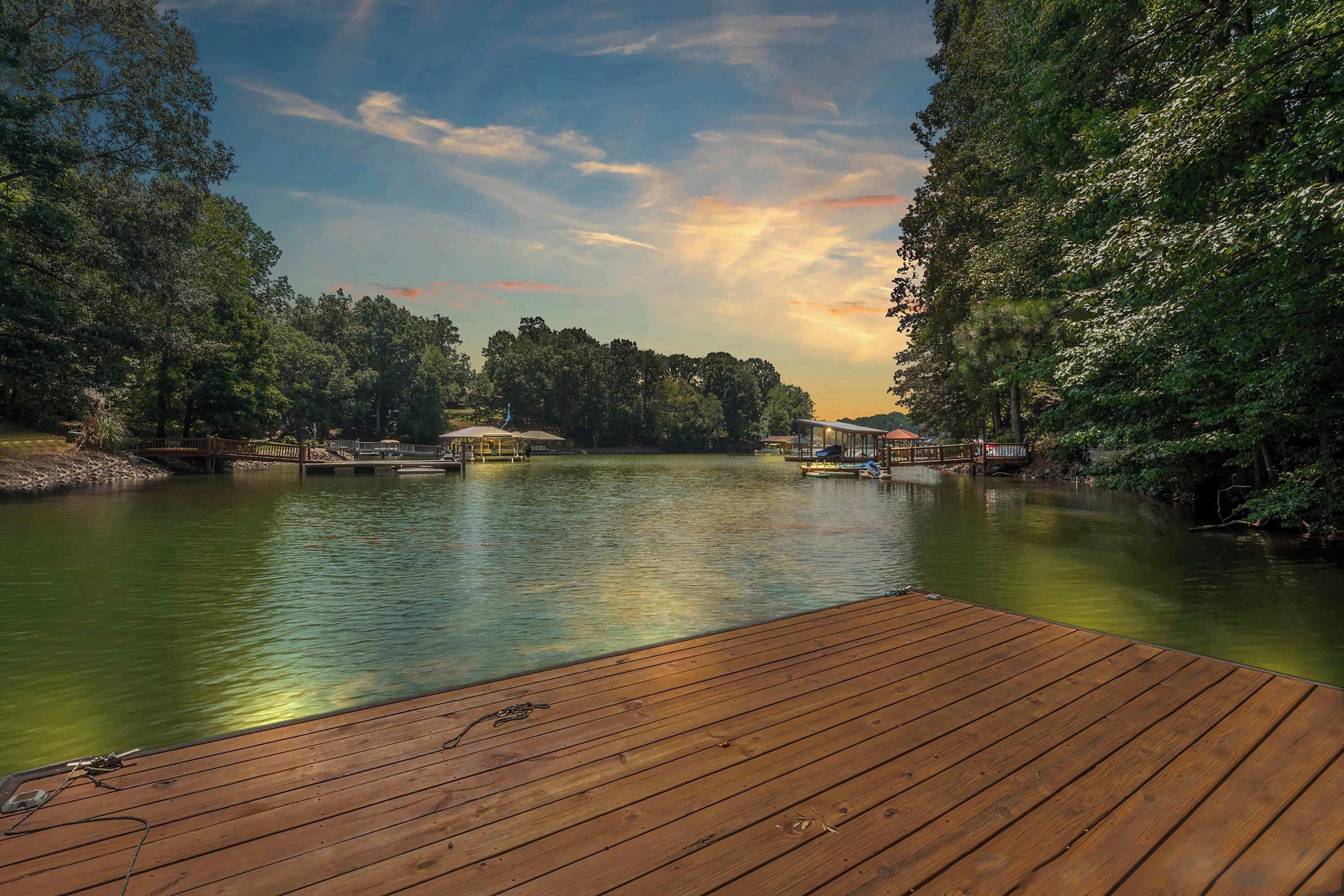 A wooden dock extending into a calm lake surrounded by dense trees, with a gazebo-like structure in the middle.