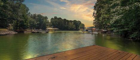A wooden dock extending into a calm lake surrounded by dense trees, with a gazebo-like structure in the middle.
