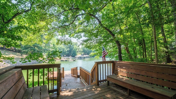Une terrasse en bois, agrémentée de bancs, qui offre une vue sur une rivière paisible, le tout entouré d’une végétation luxuriante.