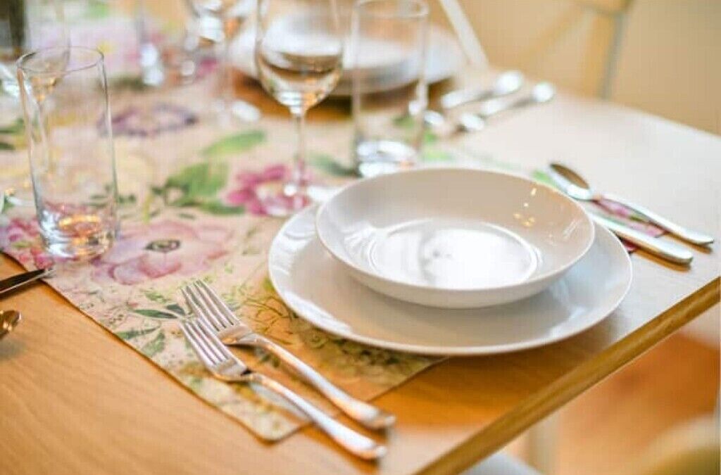 A table set with a white plate, silverware, and a glass of water.