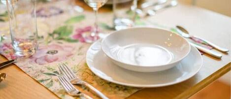 A table set with a white plate, silverware, and a glass of water.