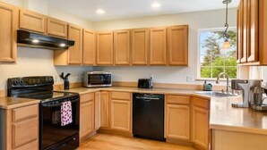 A modern kitchen with wooden cabinets, a black stove, a microwave, and a dishwasher. - Cozy 2BR Apt, Hot tub, King bed, secluded, and freshly remodeled!
 (Juneau)