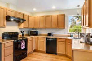 A modern kitchen with wooden cabinets, a black stove, a microwave, and a dishwasher. - Cozy 2BR Apt, Hot tub, King bed, secluded, and freshly remodeled!
 (Juneau)