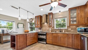 Une cuisine moderne avec des meubles en bois, des appareils électroménagers en acier inoxydable et un grand îlot central.