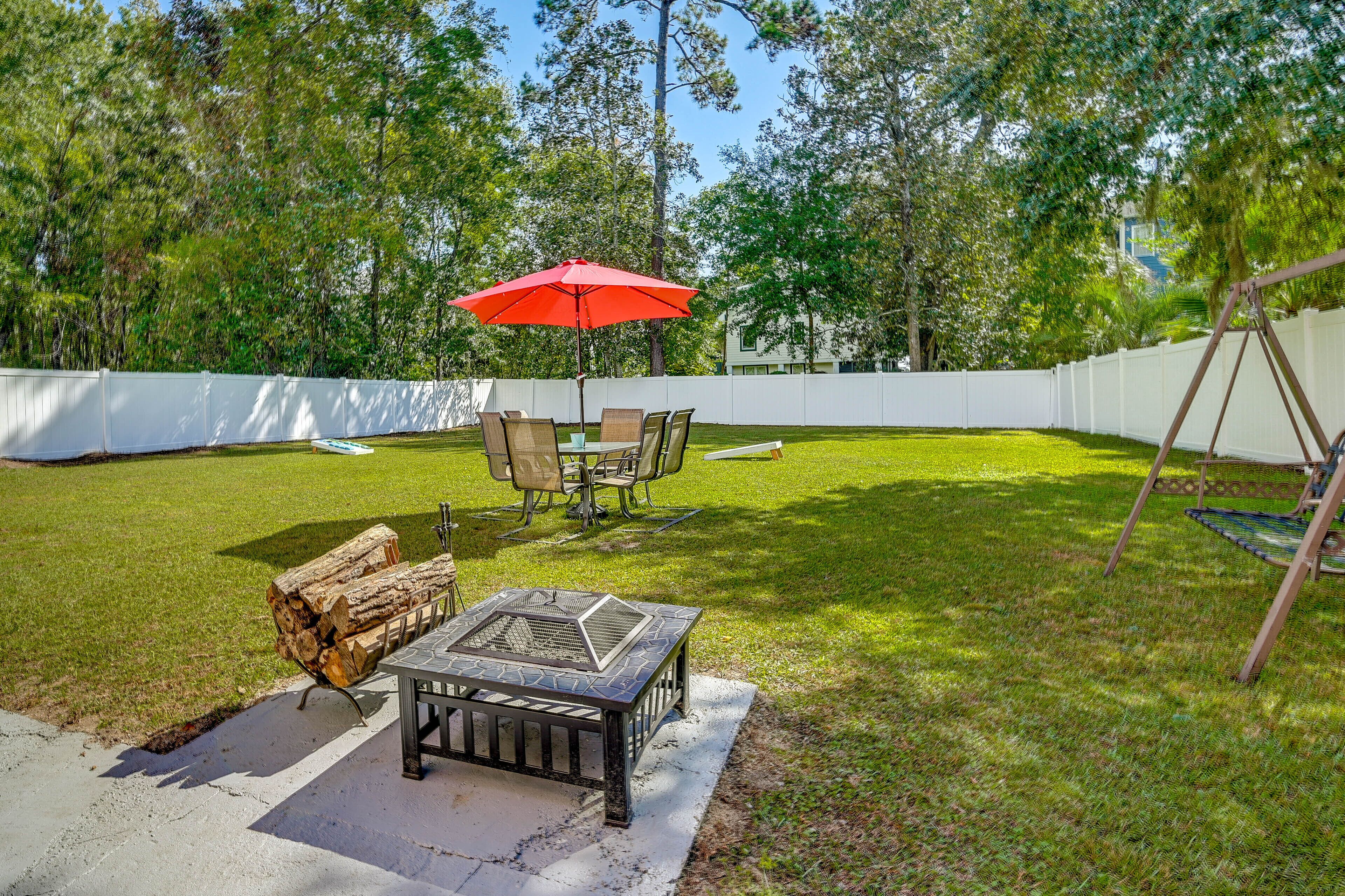 A backyard with a fire pit, outdoor furniture, and a swing set.