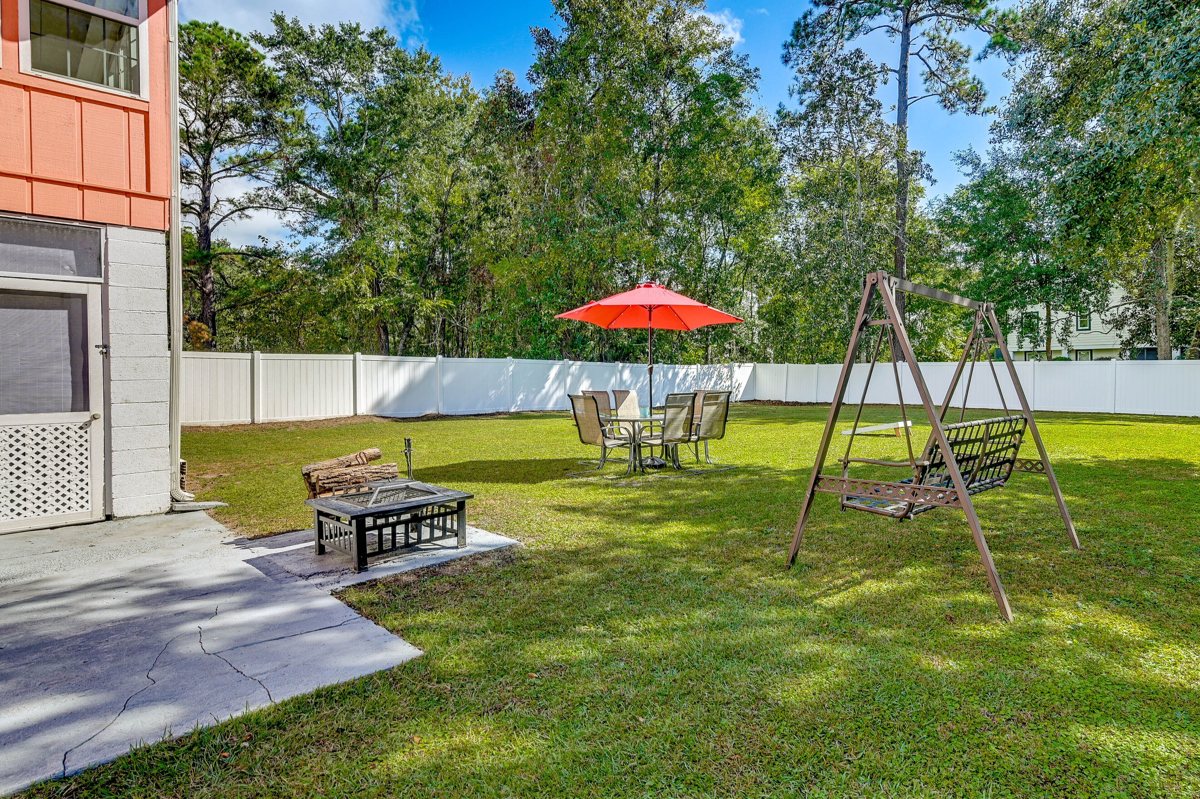 A backyard with a swing set, picnic table, and umbrella.