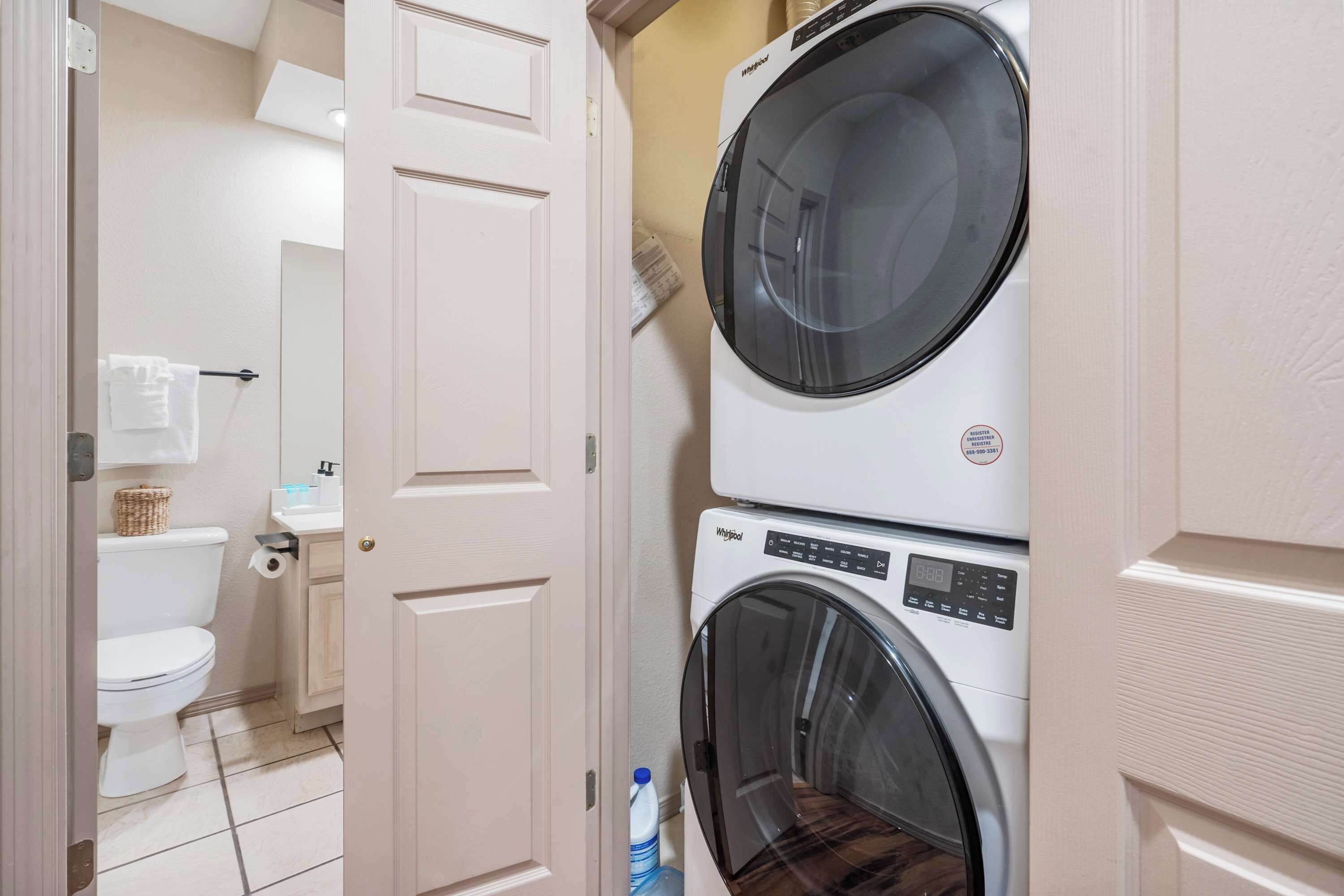 A laundry room with a stacked washer and dryer, a toilet, and a sink.