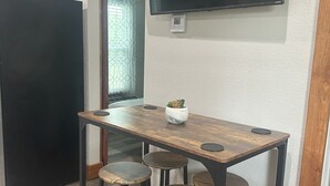 Eine moderne Küche mit Holztisch, Barhocker und einem wandmontierten Flachbildfernseher.