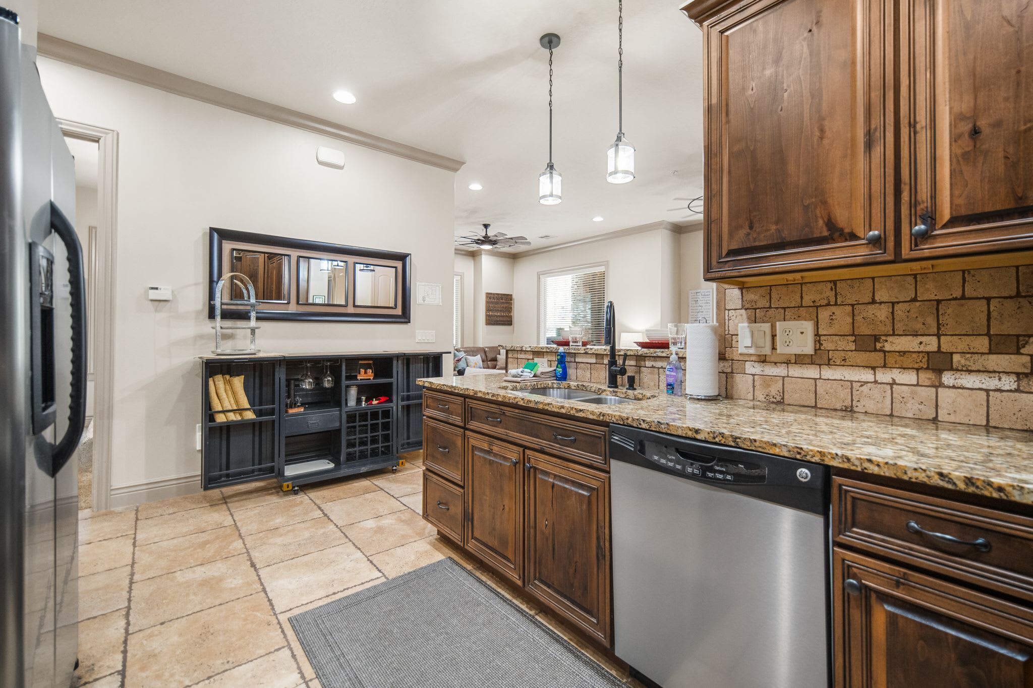 A kitchen with granite countertops, wooden cabinets, a dishwasher, and a built-in wine cooler.