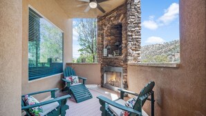 Un patio con chimenea de piedra, sillas Adirondack verdes y vistas del paisaje circundante.