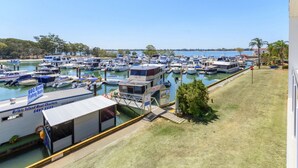 Un puerto deportivo con varias embarcaciones amarradas, un servicio de alquiler de barcos y una zona verde con un edificio.